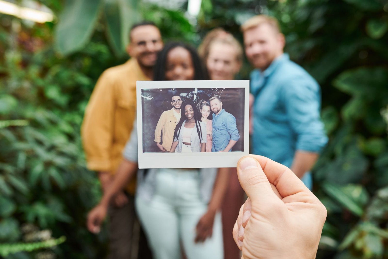 Retaining Your Best People Certification - A group of friends enjoying a moment with an instant camera photo surrounded by lush greenery.