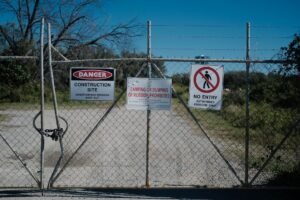 Unauthorised Personnel - Metal gate with warning signs at a construction site prohibiting entry and dumping.