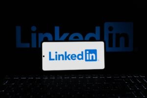 Introduction to Social Media Careers Certification - Smartphone showing LinkedIn logo with keyboard and large background logo, business theme.