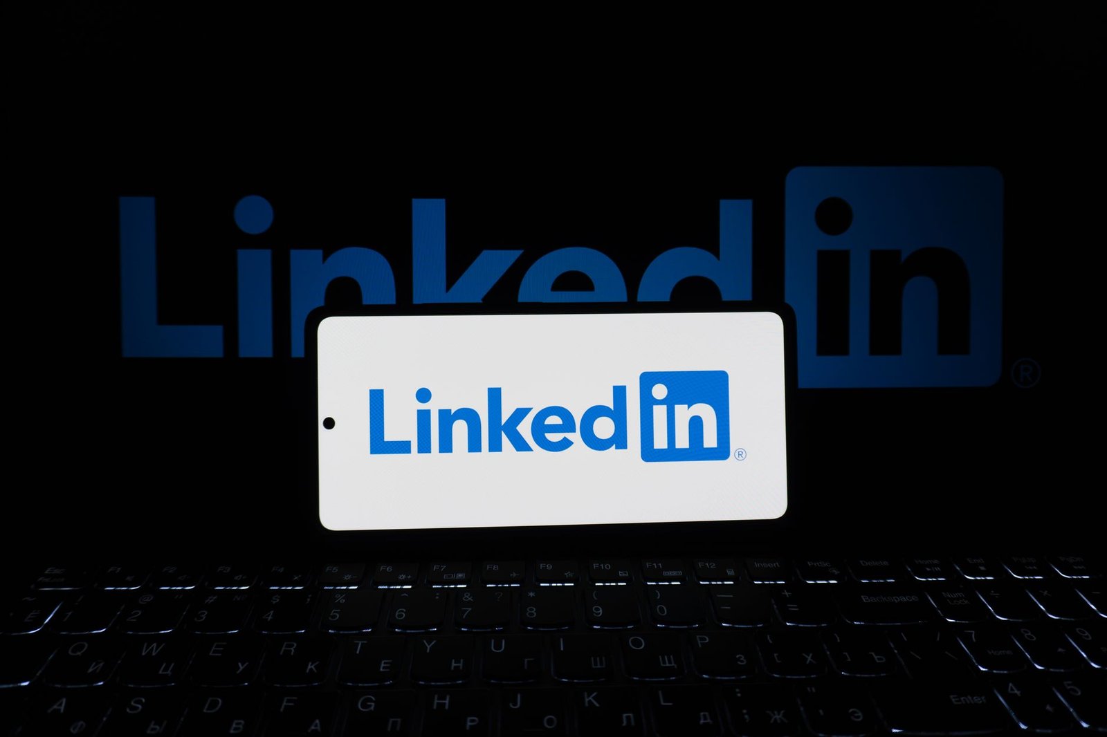 Introduction to Social Media Careers Certification - Smartphone showing LinkedIn logo with keyboard and large background logo, business theme.