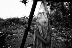 Female Genital Mutilation, Abuse & Forced Marriage Awareness Training - A child holding a sheet outdoors, obscured, in a monochromatic scene.
