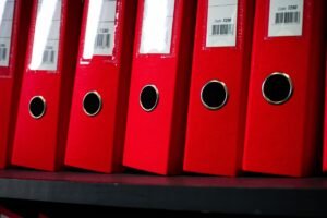 Organisational Skills for Administrators Certification - Close-up view of red office binders neatly organized on a shelf.