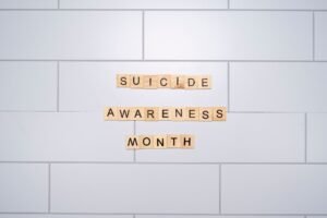 Suicide Prevention Certification - Suicide Awareness Month spelled with Scrabble tiles on a light background symbolizes mental health awareness.
