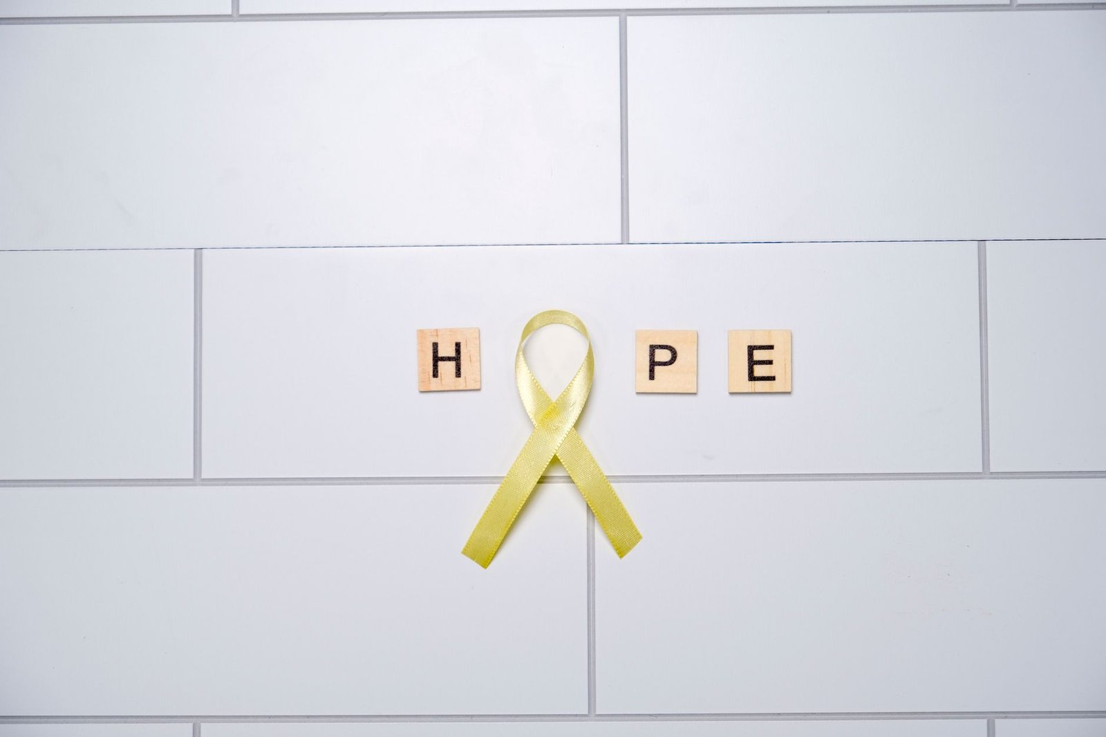 Mental Health Awareness Certification - A yellow ribbon forming the word 'hope' with tiles on a white tiled background, symbolizing awareness and support.
