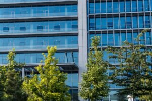 Corporate Sustainability Certification - Contemporary glass office building facade with trees in front, reflecting urban environment.