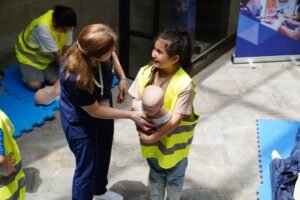 Paediatric First Aid Certification - Child participates in a hands-on first aid class learning infant care with an instructor.