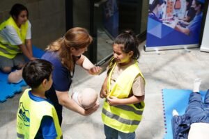 Health and Safety in the Workplace (UK) Certification - Kids and instructor learning CPR techniques during first aid safety training.