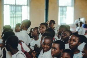 Improving School Attendance Certification - A diverse group of students attentively participating in an indoor school assembly.