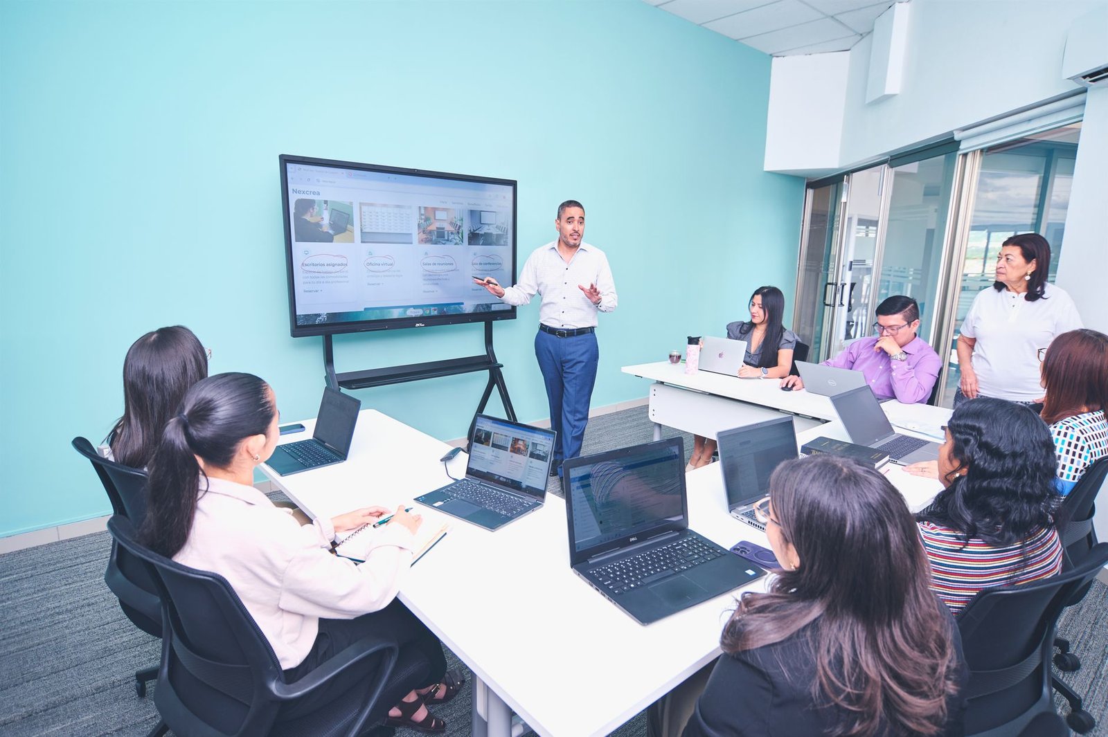 Managing Teams Certification - Team engaged in a presentation at a modern office using digital technology.