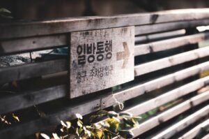 Decoding Direct/Indirect Messages Certification - Wooden fence with a directional sign in Korean lit by sunlight.