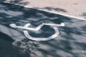 Disability Awareness Certification - Close-up of an accessible parking symbol on a sunlit asphalt road.