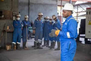 Developing Employees Certification - A group of factory workers in safety gear receiving training indoors.
