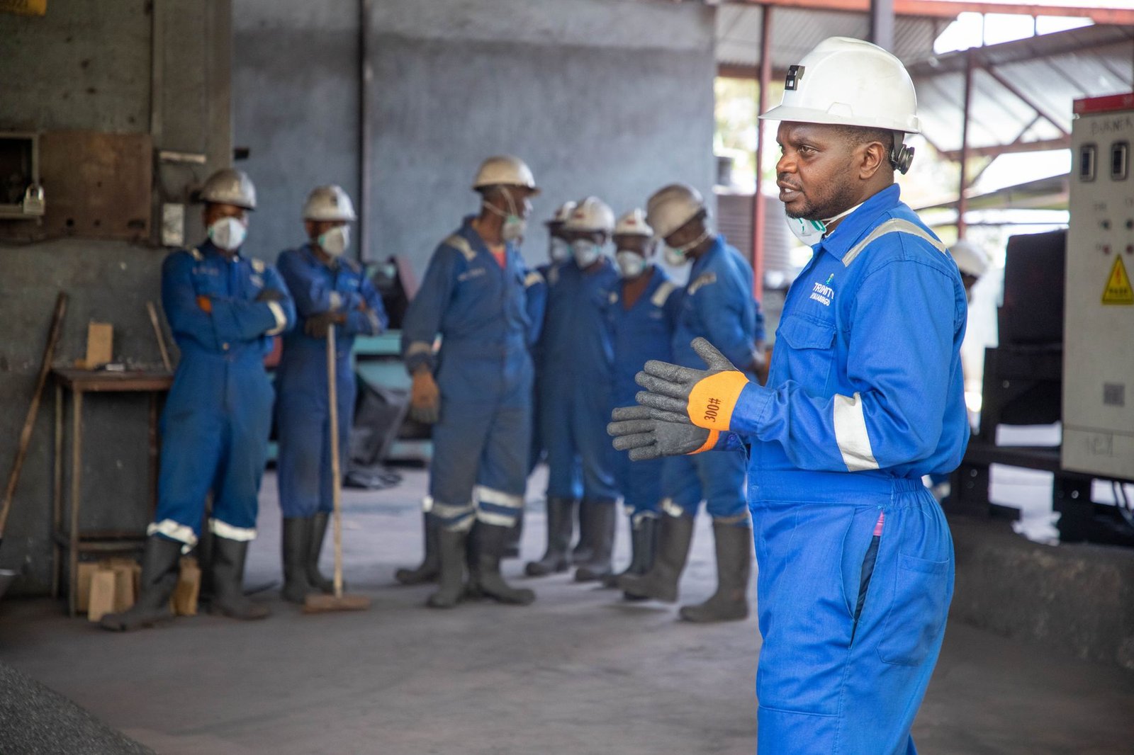 Developing Employees Certification - A group of factory workers in safety gear receiving training indoors.