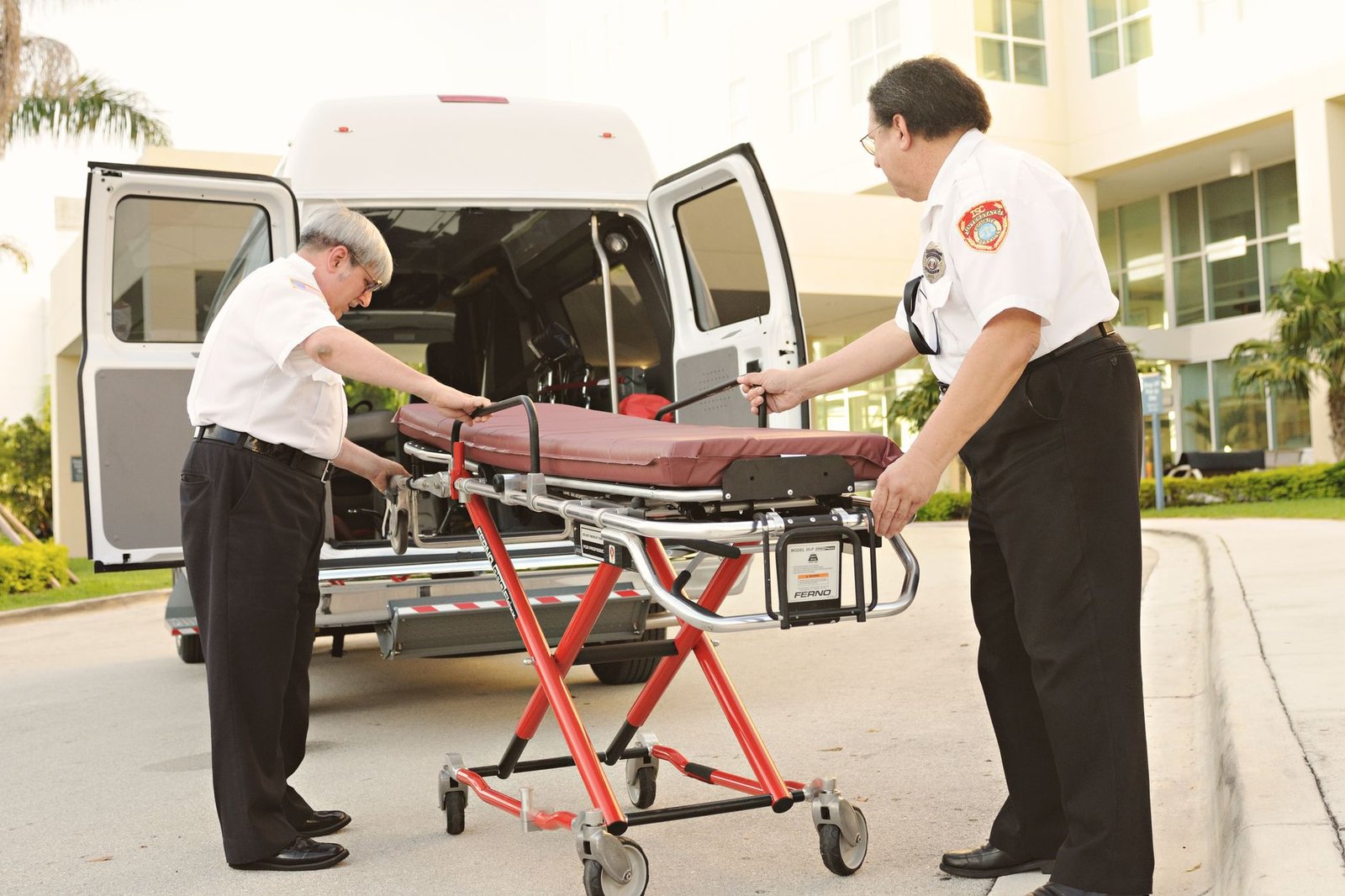 People Handling Certification - Two EMTs handle a stretcher outside a building, readying for patient transport.