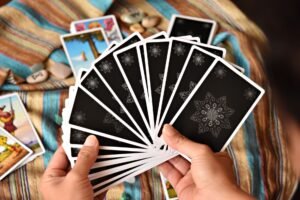Tarot Card Reading Certification - Hands holding tarot cards during a reading session on a colorful fabric background.