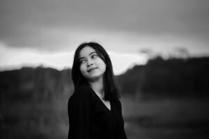 Introduction to Photography Certification - A captivating black and white portrait of a young woman looking upwards outdoors.