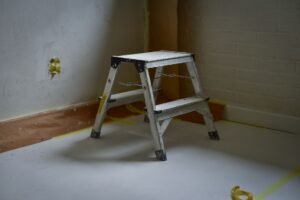 Step Ladder Safety Awareness Certification - A sturdy metal ladder placed on a taped-off floor in a room under renovation.