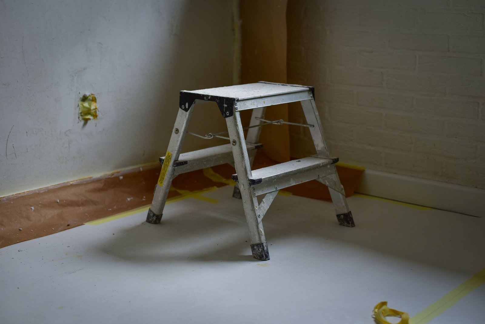 Step Ladder Safety Awareness Certification - A sturdy metal ladder placed on a taped-off floor in a room under renovation.