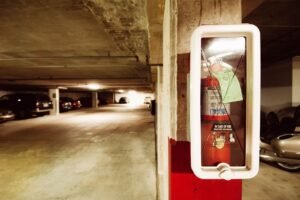 Understanding Fire Extinguishers Certification - Fire extinguisher in an underground parking garage with parked cars.