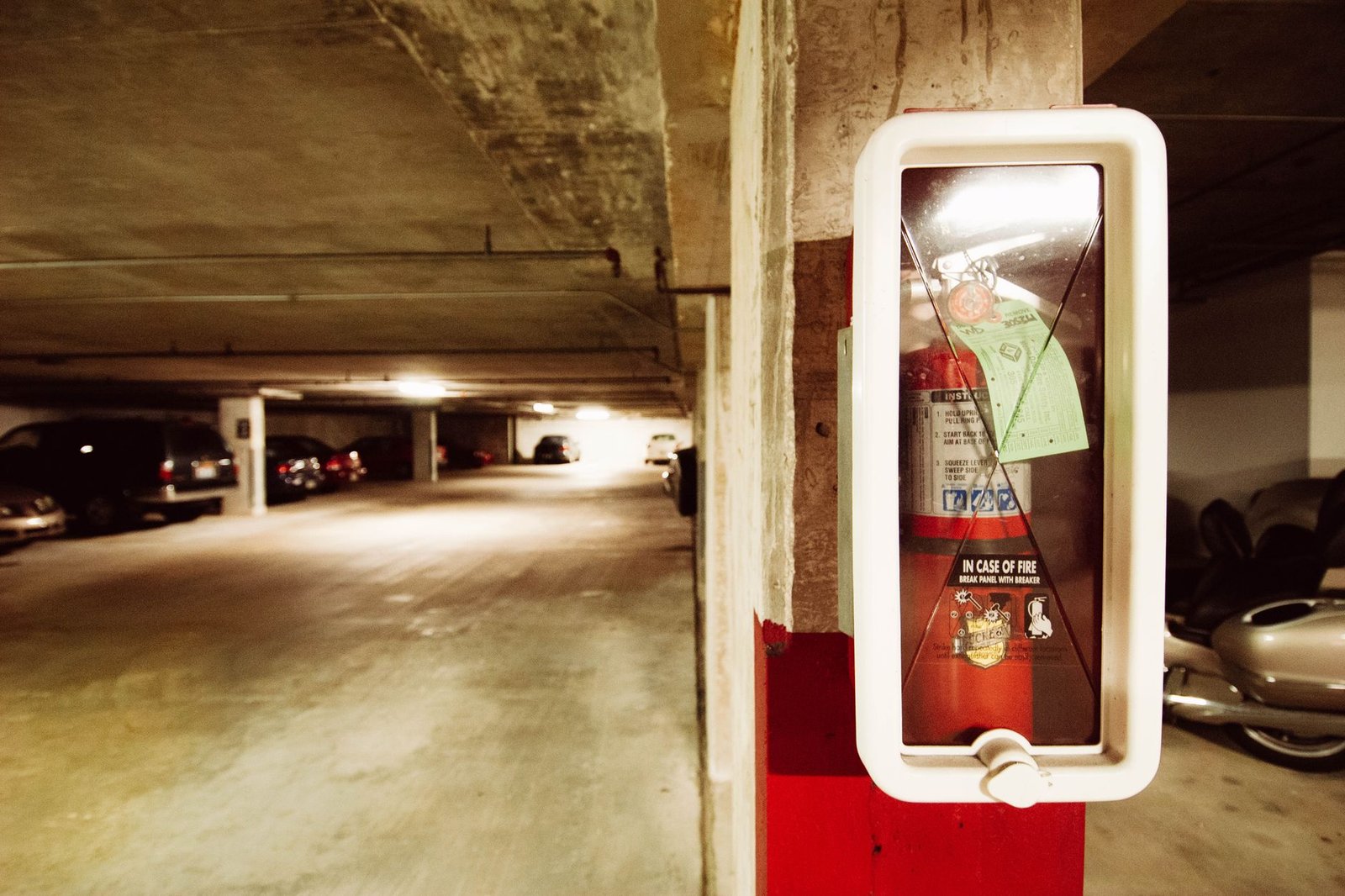 Understanding Fire Extinguishers Certification - Fire extinguisher in an underground parking garage with parked cars.