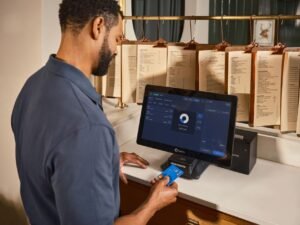 Xero UK Certification - A restaurant staff member uses a POS system to process a credit card payment at the counter.