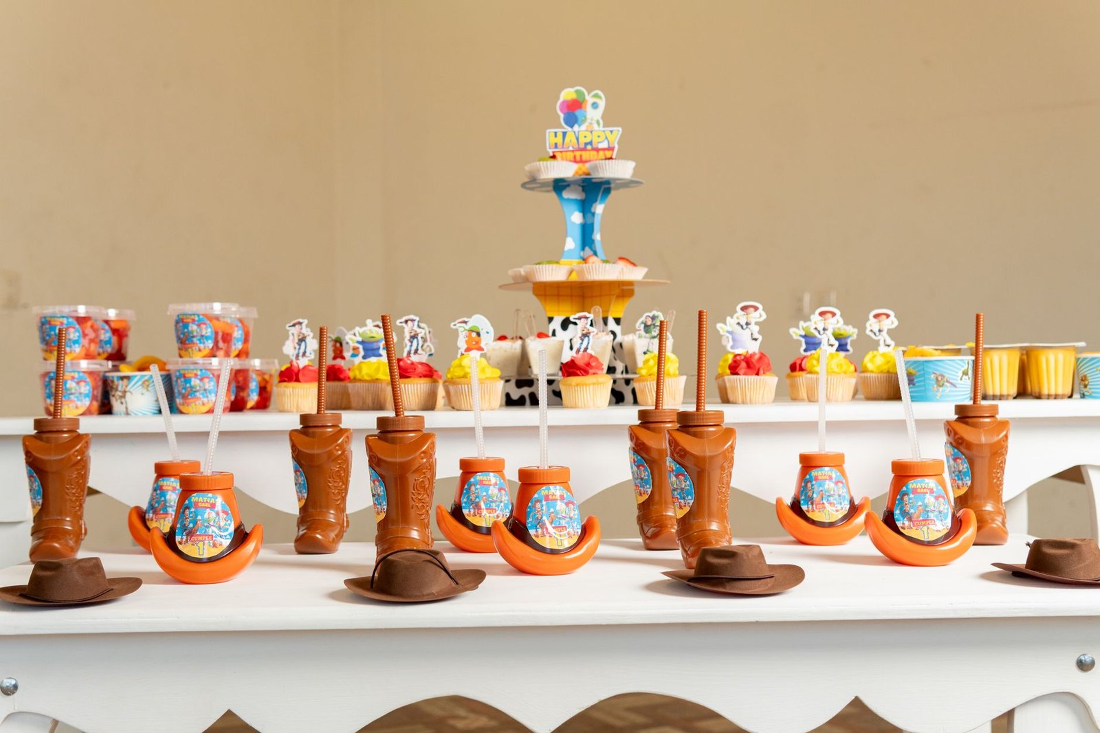 Cupcake Decorating – Birthday Ideas Pack 1 - Colorful toy-themed birthday party table with decorations, cupcakes, and creative cowboy boot cups.