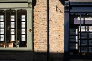 Estate Agency – Scottish System Certification - Sunlit display windows of an estate agency in Malmesbury, England.