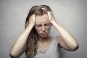 Stress, Anxiety, Depression & Violence in the Workplace Training - Young woman expressing stress and frustration while holding her head.