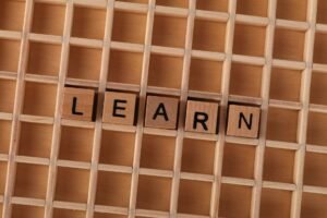 Learning to Learn Certification - Wooden blocks spelling the word 'LEARN' on a grid-like wooden background. Educational concept.