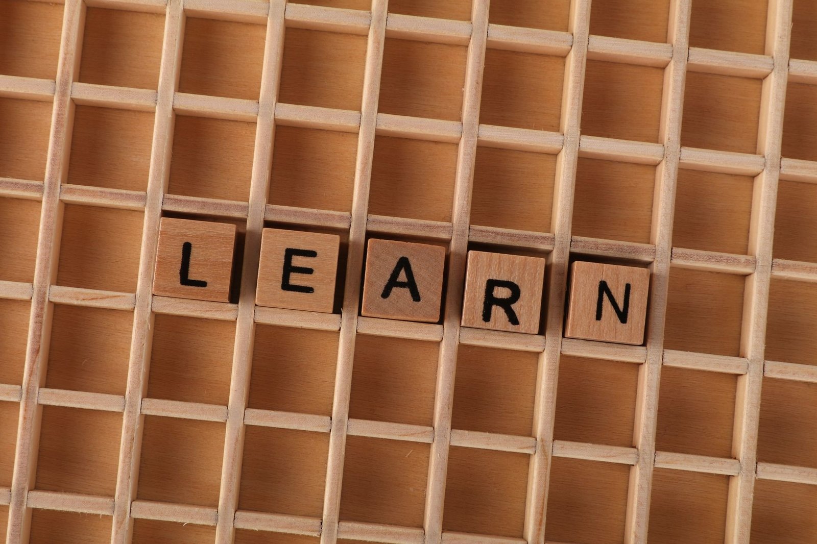 Learning to Learn Certification - Wooden blocks spelling the word 'LEARN' on a grid-like wooden background. Educational concept.