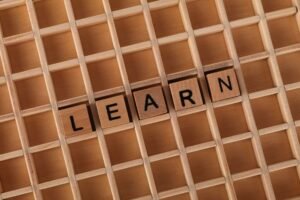 Learning Strategies Certification - Wooden letter blocks spelling 'Learn' placed on a wooden grid background.
