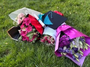 Floristry Academy Diploma - Graduation cap with colorful flower bouquets and diploma on green grass.