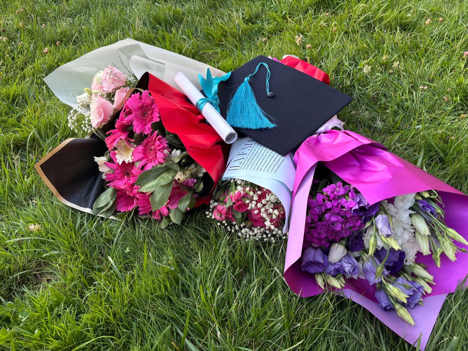 Floristry Academy Diploma - Graduation cap with colorful flower bouquets and diploma on green grass.