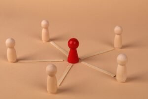 Delegation of Authority Certification - Wooden figures with red leader representing teamwork and influence.