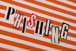 Psychology of Phishing - Conceptual image of the word 'Phishing' using cut-out letters on an orange striped background.