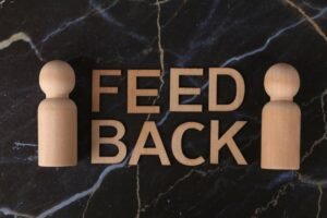 Constructive Feedback Certification - Wooden letters spelling 'Feedback' with peg-like figures on marble background.