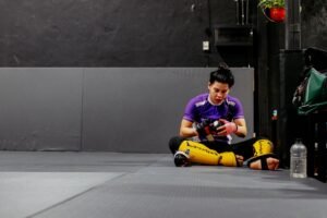 Discipline and Grievance Certification - A female martial artist sits on the gym floor during a break. Focused and ready.