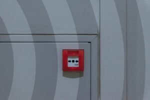 Understanding the PAYE System Certification - Red emergency button on a grey patterned wall, emphasizing safety measures.