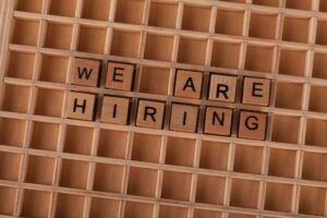 Hiring for a Diverse Workforce Certification - Wooden tiles on a board forming the phrase 'We Are Hiring', ideal for job announcements.