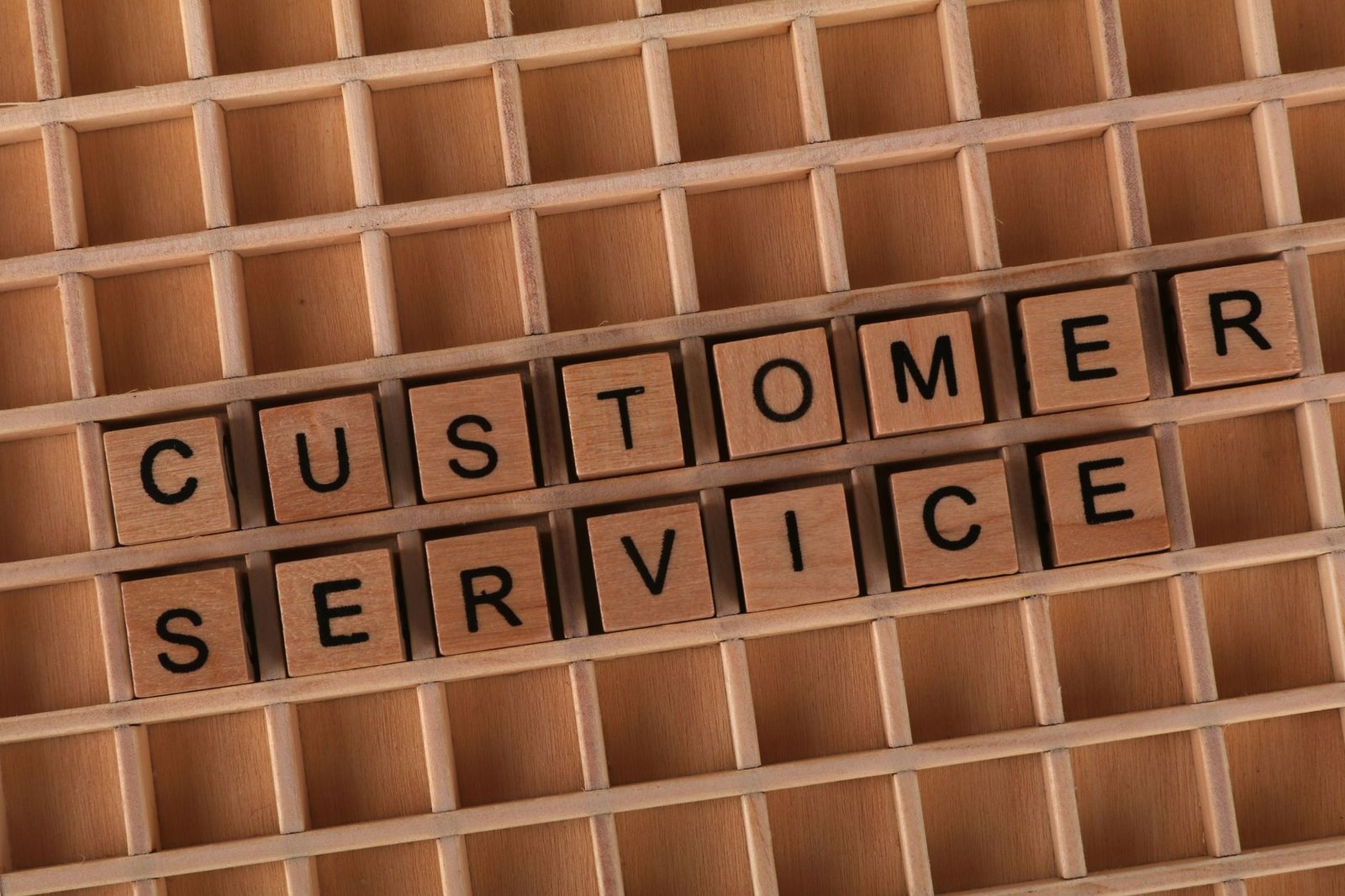 Caring for your Customers’ Needs Certification - Wooden blocks forming the phrase 'Customer Service' placed inside a wooden grid, symbolizing support and assistance.