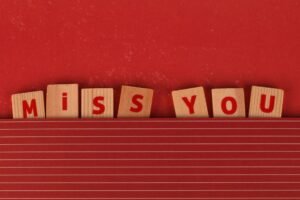 Absence Management Certification - Wooden blocks with 'MISS YOU' text on a red background, expressing longing.