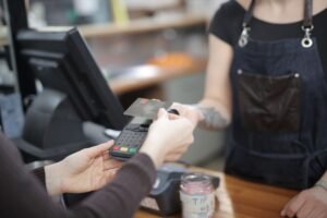 When Employees Pay Less than the NIC Certification - Close-up of customer and cashier during a credit card transaction at a store counter indoors.
