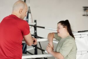 Supporting People with Physical Disabilities Certification - Two people engage in a supportive conversation in a boxing gym.