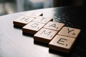 Lockdown Training Certification - High angle of scrabble letter tiles arranged on black wooden table in inscription Stay Home in living room