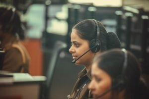 Telephone Customer Services Certification - Side view of a call center agent wearing a headset, working diligently in a busy office environment.
