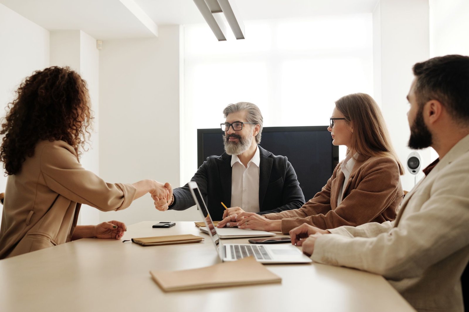 Human Capital Management Certification - Colleagues in an office celebrating a successful negotiation with a handshake.