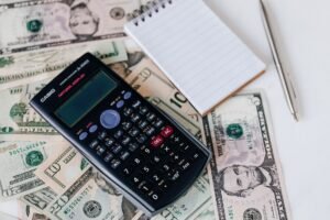 Costs and Causes of Employee Turnover Certification - From above electronic calculator and notepad placed over United States dollar bills together with metallic pen for budget planning and calculation
