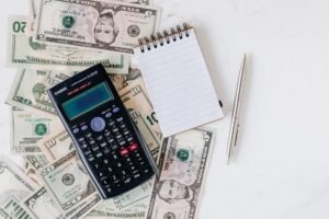 The Cash Flow Statement Certification - Top view of electronic calculator and notepad placed over United States dollar cash money together with metallic pen for budget planning and calculation
