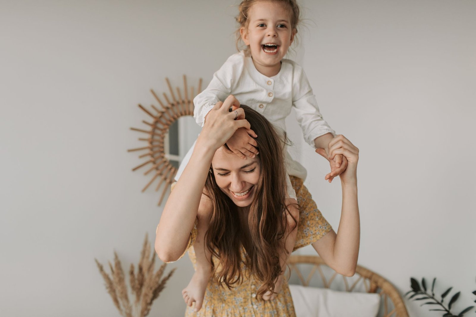 Child Attachment Certification - Mother and daughter enjoying a playful moment indoors, smiling and happy.