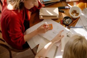 Preparing for an Exam Certification - Two students engaged in studying at a table with textbooks, notes, and stationery.